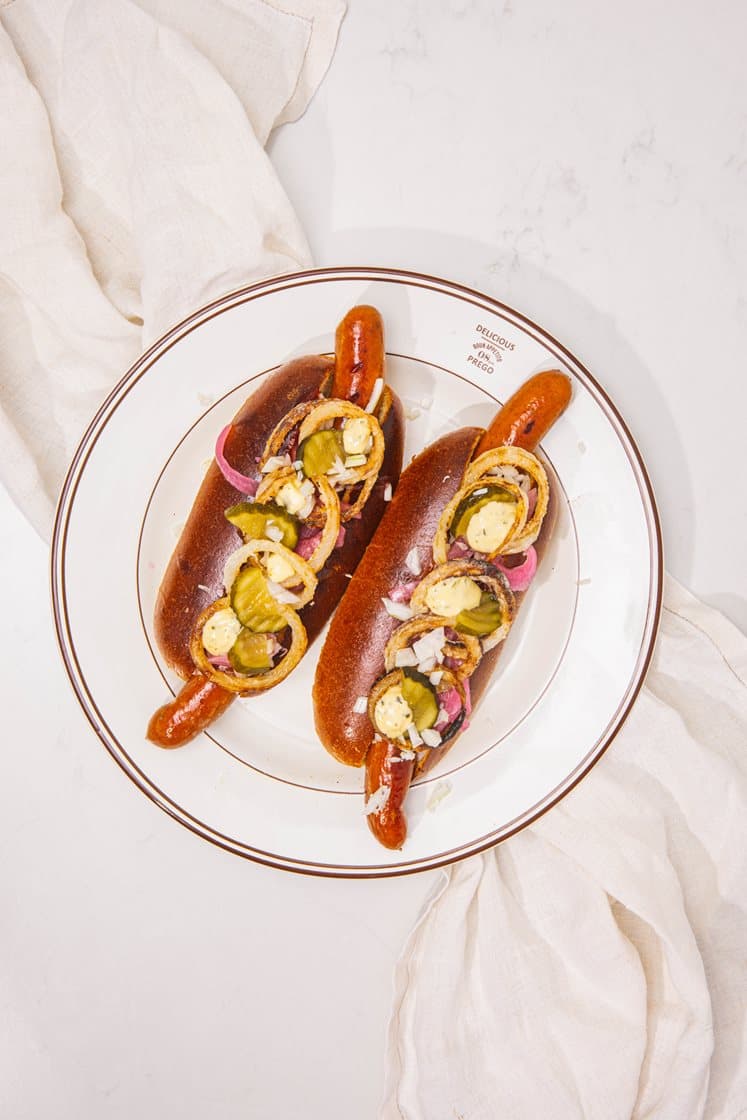 Hotdog med hjemmeristede løg, syltede rødløg og drueagurk