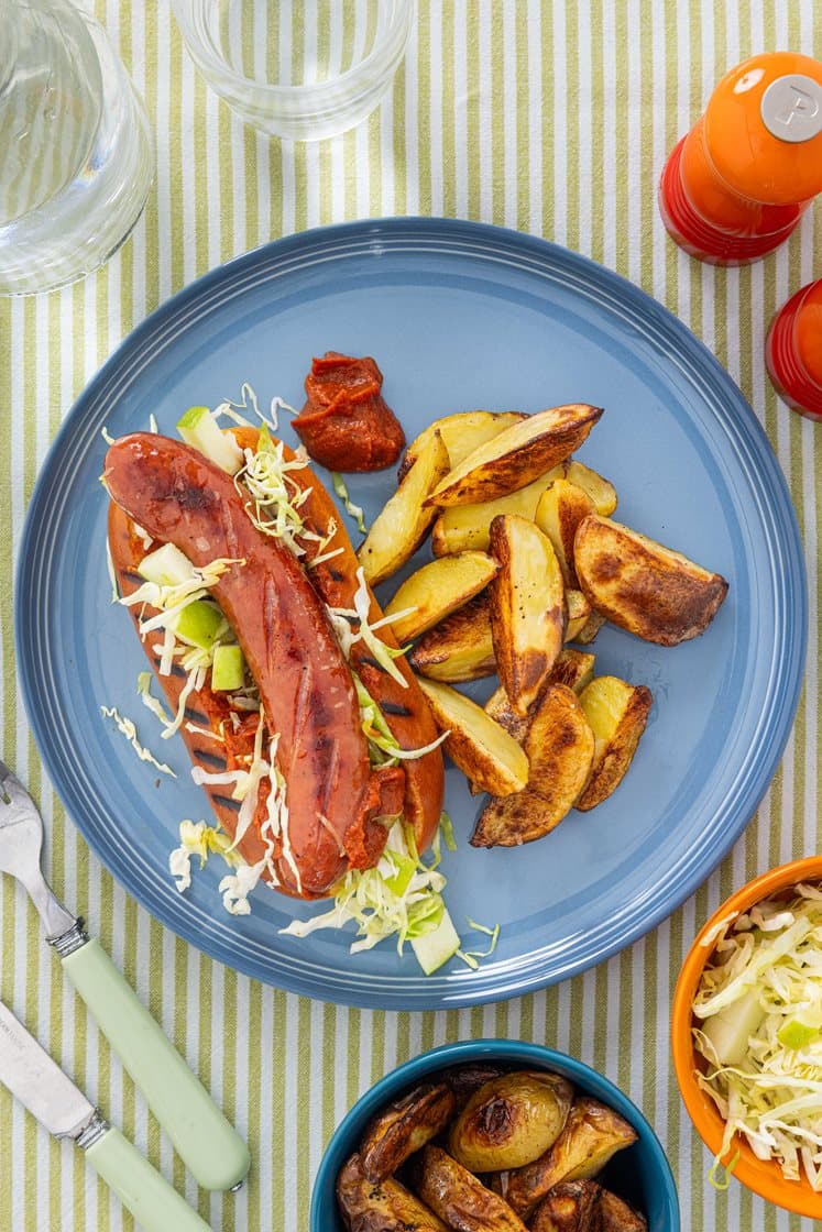Hotdog med karry-ketchup, sur spidskål med æble og kartoffelbåde
