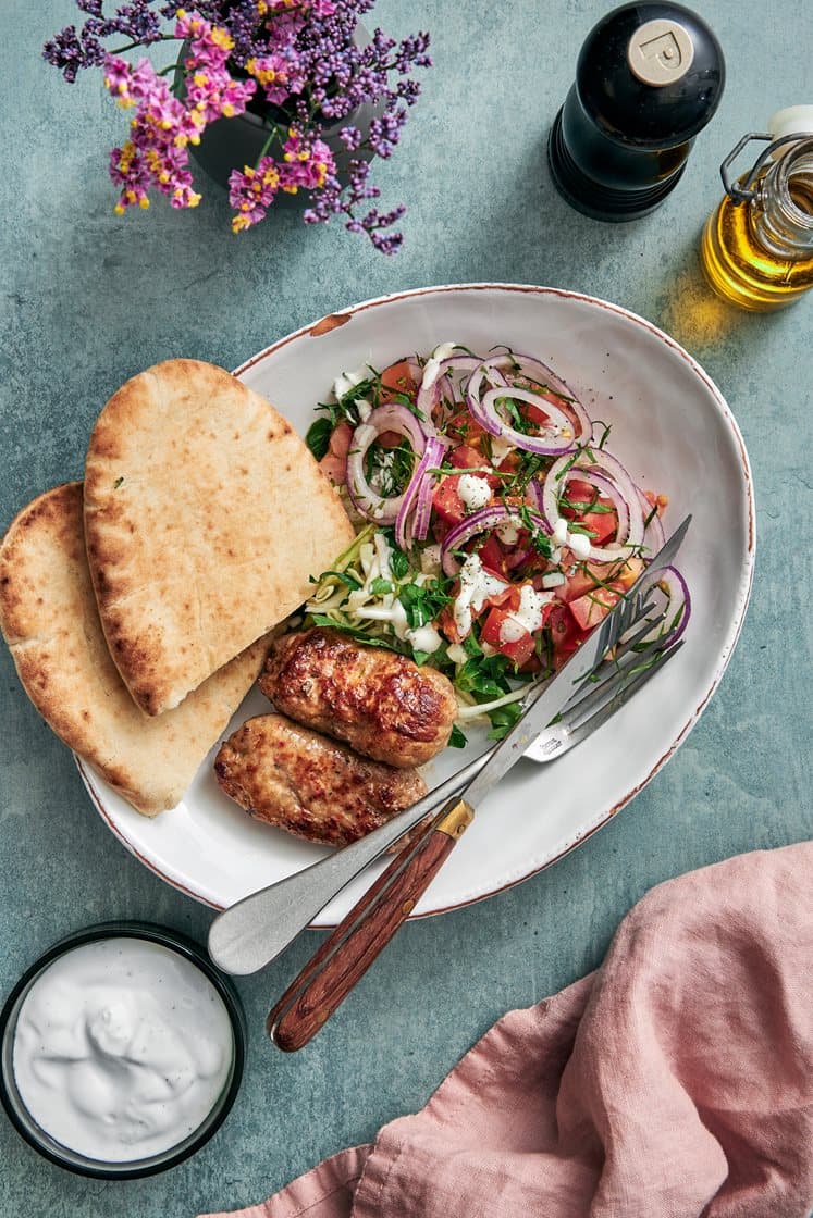 Italiensk salsiccia-kebab i pitabrød med citronmarineret kål og tomatsalat